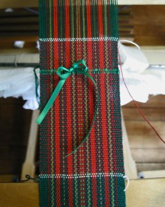 Photo of red and green striped fabric for Holiday Cards on the loom - woven by Joanne Littler, Pine Ledge Fiber Studio, Fairfax, VT , 2011n 2011